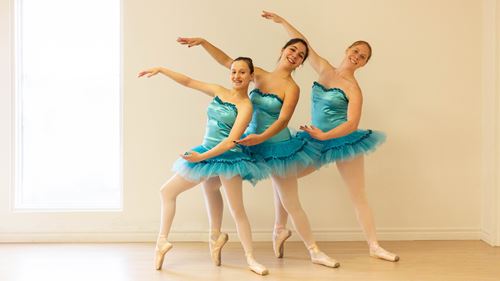 Graceful young ballerinas in blue tutus rehearsing classical ballet.