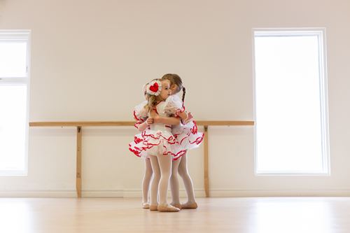 Enfants en danse classique dans un studio lumineux avec barres de ballet.