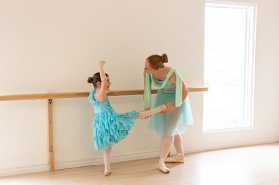 Enfant danseuse classique avec professeur dans un studio de danse pédagogique.