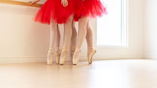 Chaussures de ballet sur pointes de jeunes danseuses en tutu rouge.